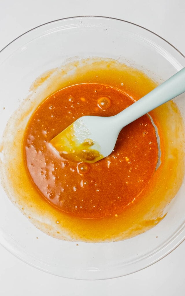 orange brownie batter in a glass mixing bowl