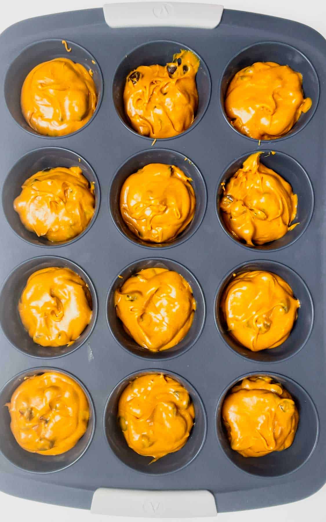 orange brownie batter in a silicone muffin pan