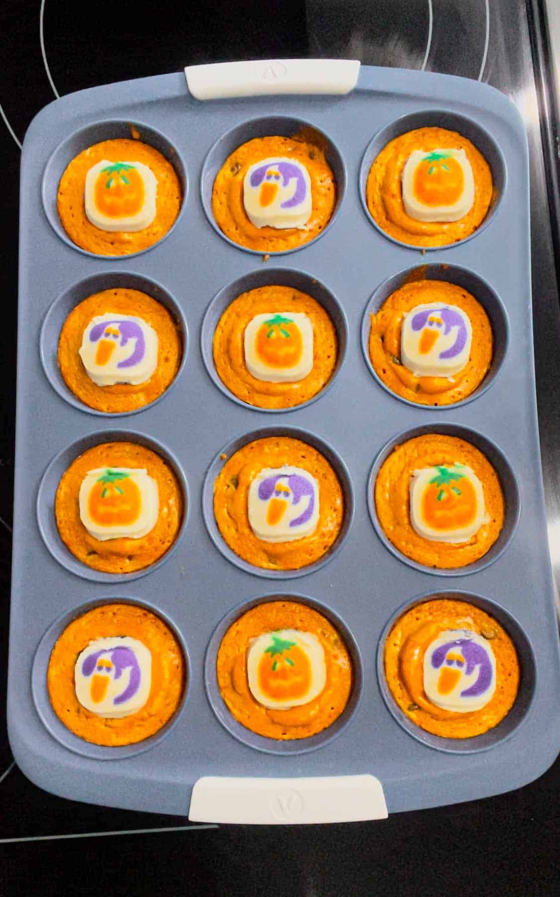 unbaked Pillsbury Halloween sugar cookies placed on top of orange brownies in a muffin tin