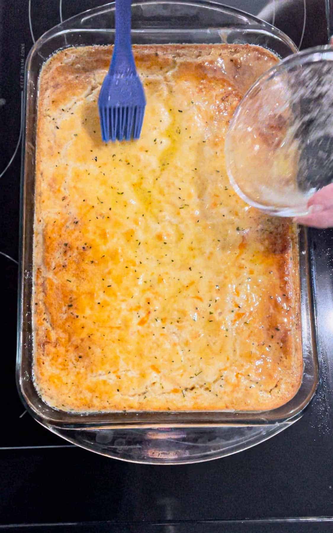 brushing butter and cheddar bay seasoning mixture on top of biscuit green bean casserole