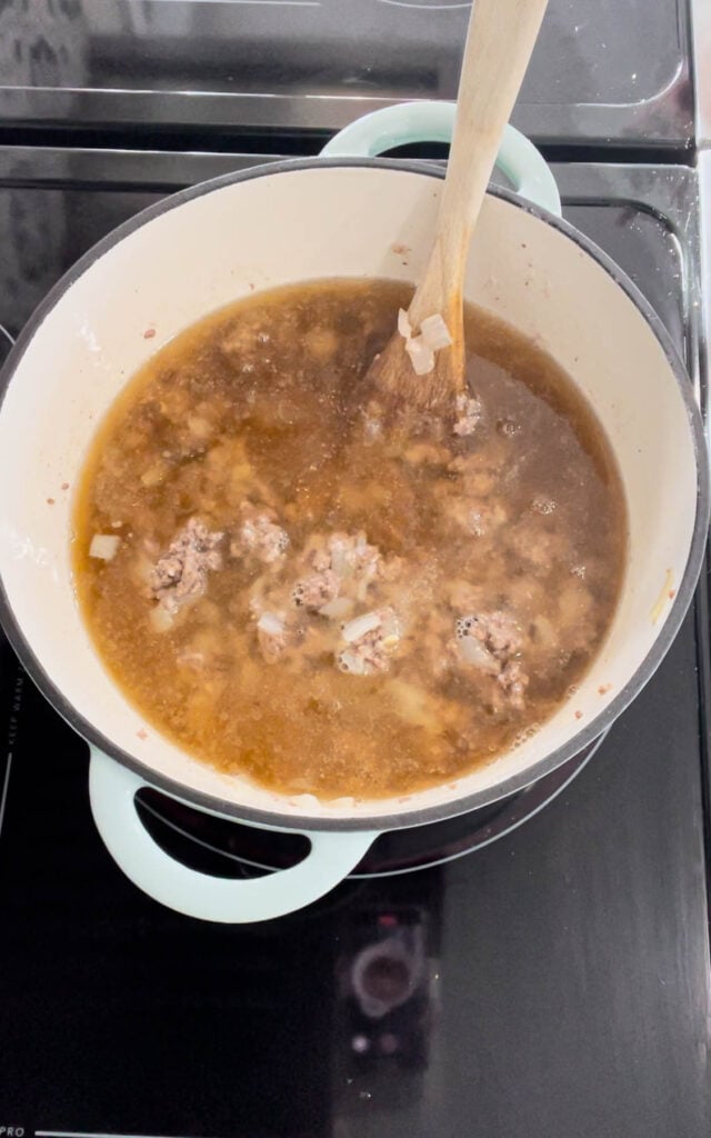 chicken broth added to pot with cooked ground beef, onion and flour mixture