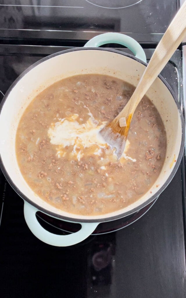 heavy cream added to broth mixture in a dutch oven