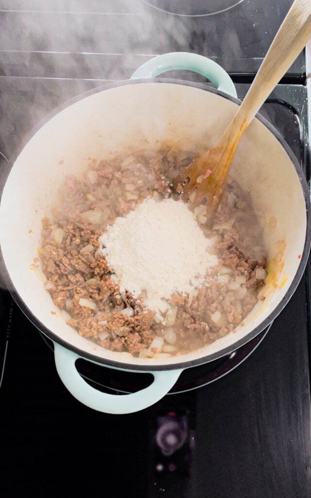 all purpose flour added to pot with cooked ground beef and diced onions