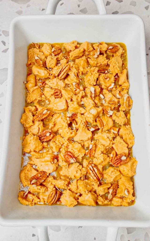pecans sprinkled over peanut butter cookie dough topping in a baking dish