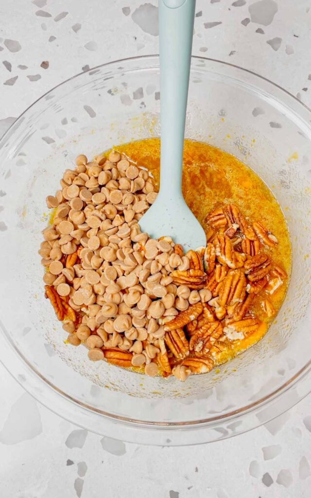 Reese's peanut butter chips and pecans added to bowl with corn syrup, sugar, butter and egg mixture