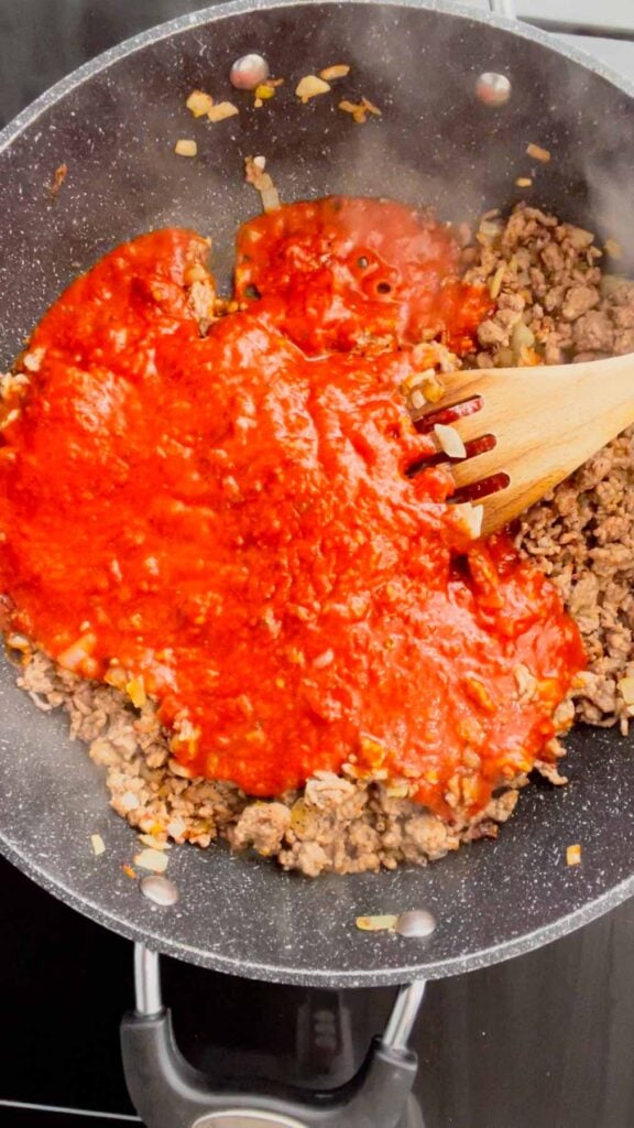 marinara sauce added to skillet with cooked ground beef