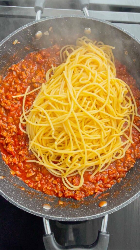 cooked spaghetti noodles added to skillet with ground beef in marinara sauce