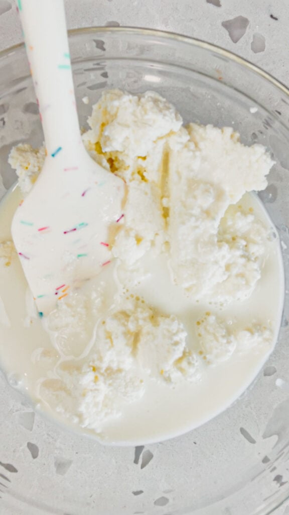 ricotta and milk in a glass mixing bowl