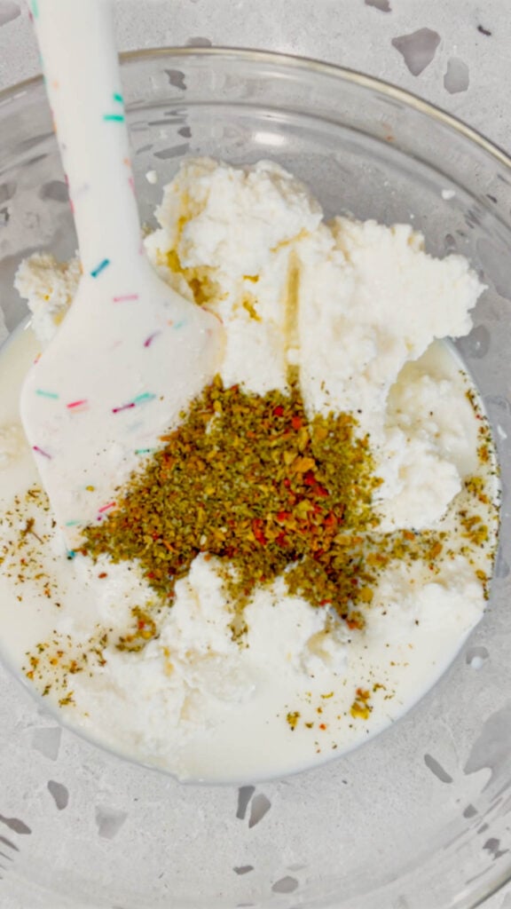 Italian seasoning added to bowl with ricotta and milk