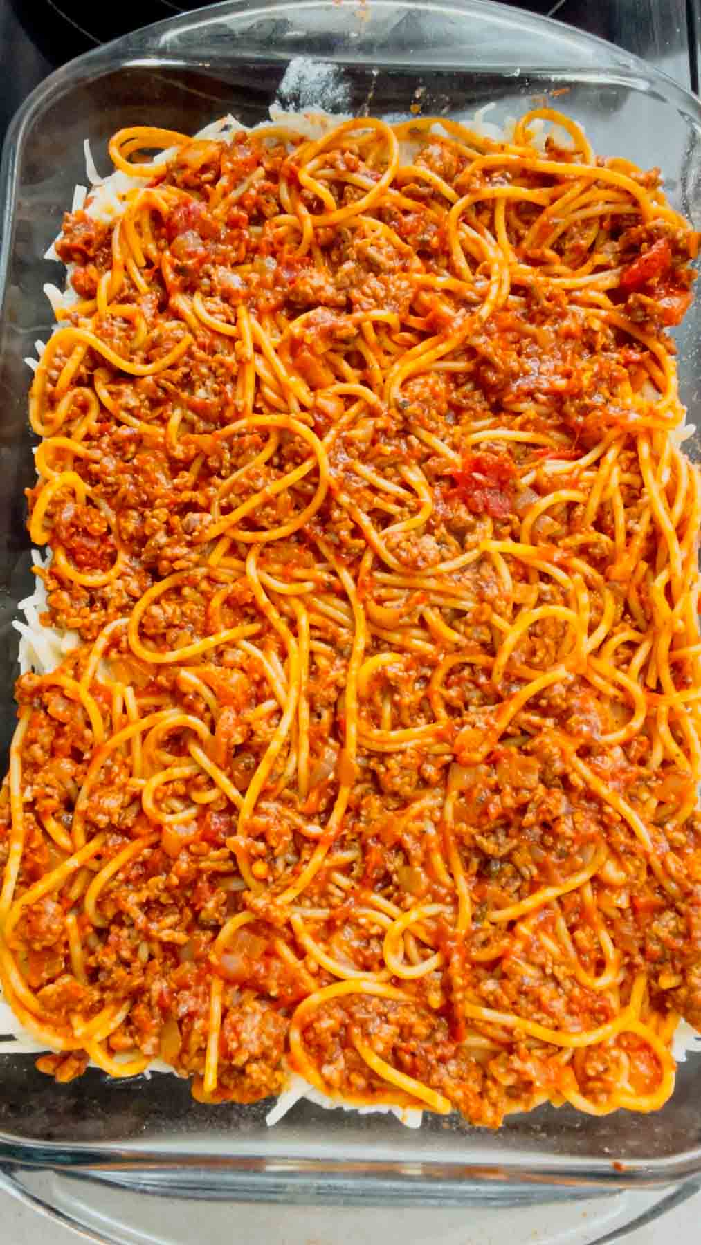 ground beef, marinara and spaghetti mixture on top of ricotta layer in a baking dish