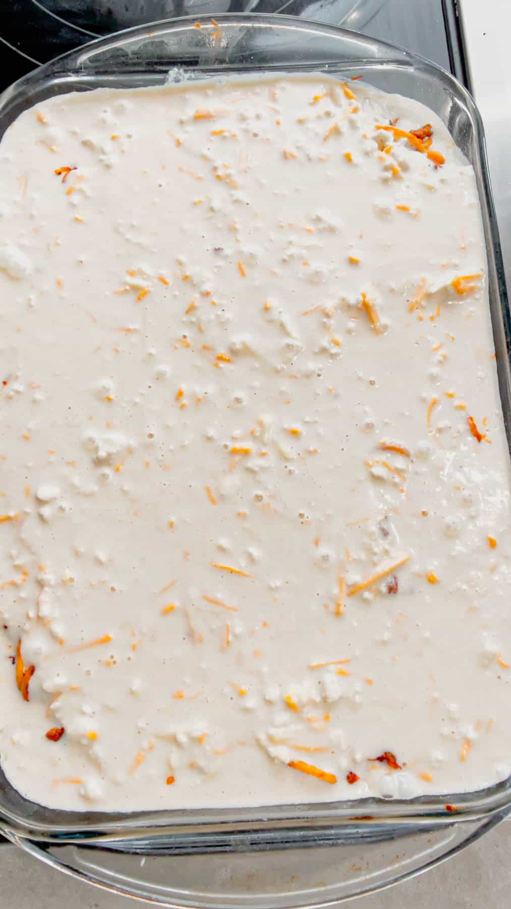 cheddar bay biscuit batter poured over spaghetti mixture in a baking dish