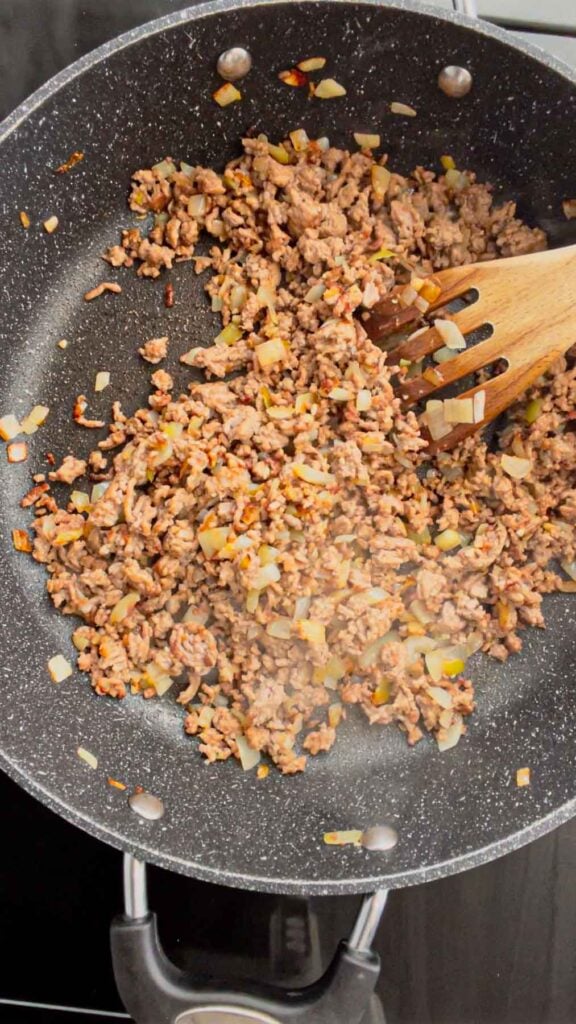 stirring chopped garlic into ground beef and onion mixture in a skillet