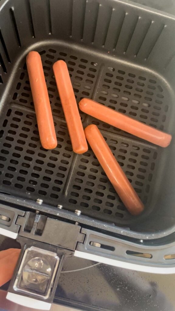 wieners in an air fryer basket before cooking