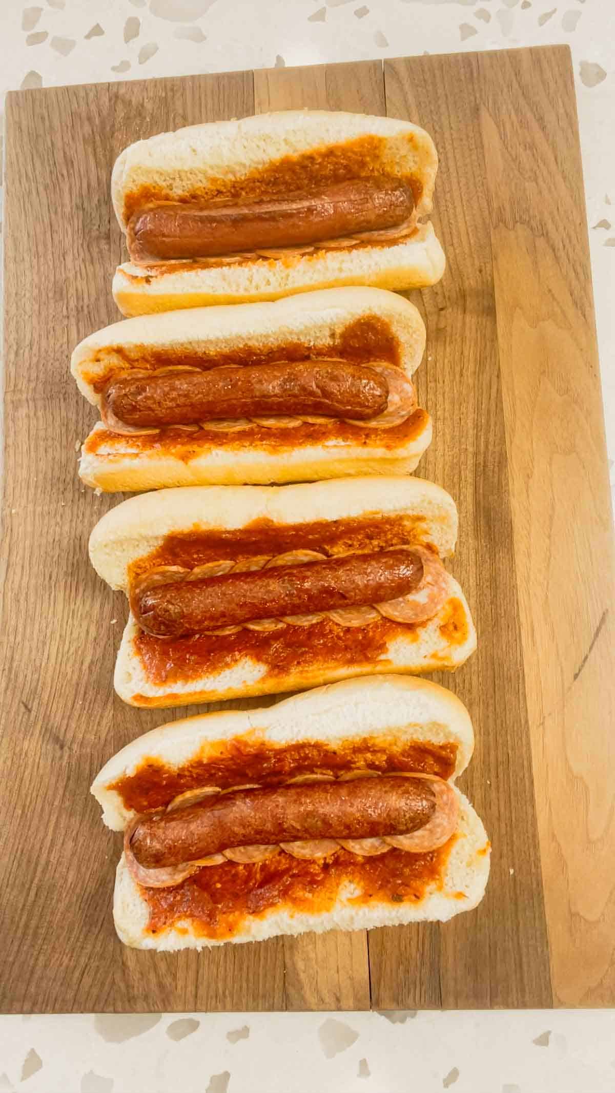 crispy wieners on top of hot dog buns spread with pizza sauce