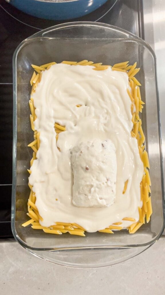 condensed cream of bacon soup and alfredo sauce on top of uncooked mini penne noodles in a baking dish