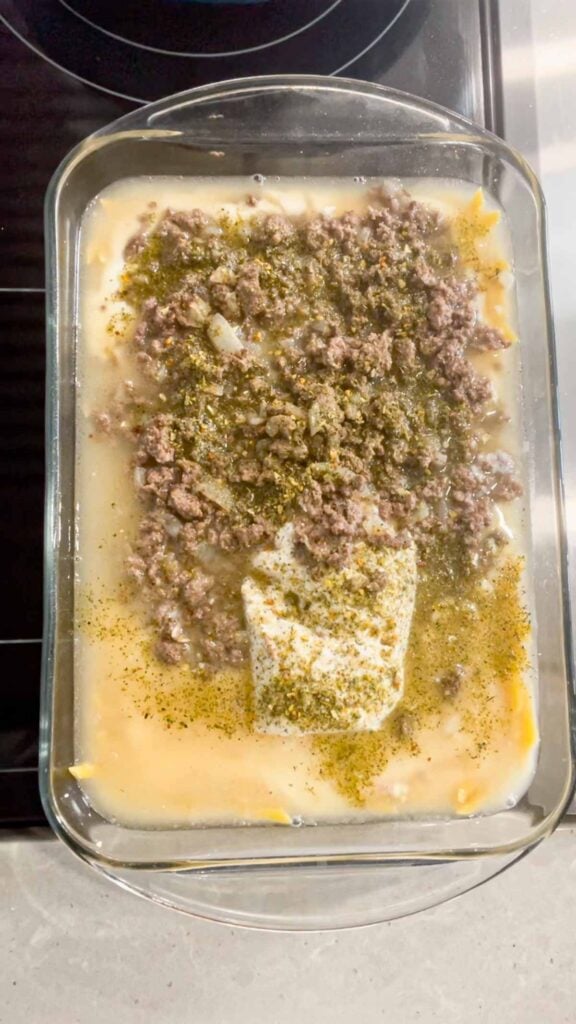 Italian seasoning, chicken broth, cooked ground beef, condensed cream of bacon soup and alfredo sauce in a glass baking dish