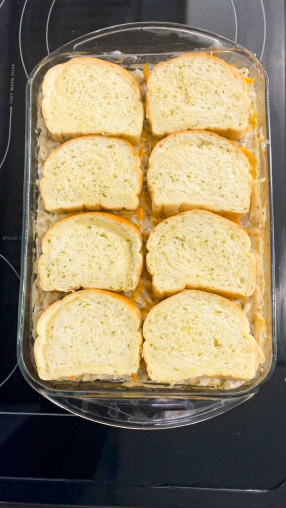 Texas toast garlic bread slices on top of ground beef alfredo in a baking dish