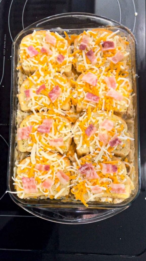 chopped bacon and shredded cheese on top of Texas toast garlic bread slices over ground beef alfredo in a baking dish