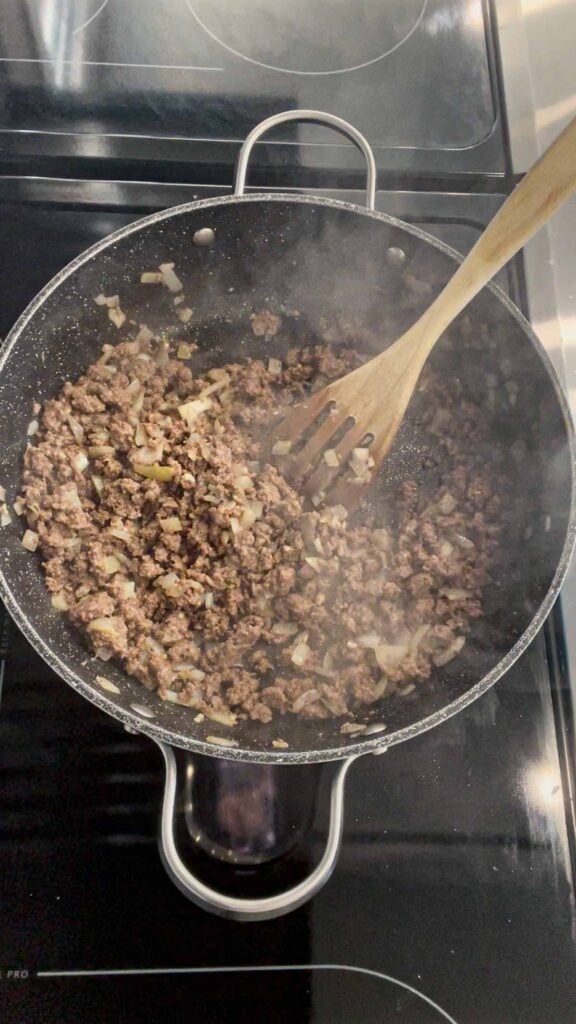 stirring chopped garlic and cooked ground beef together