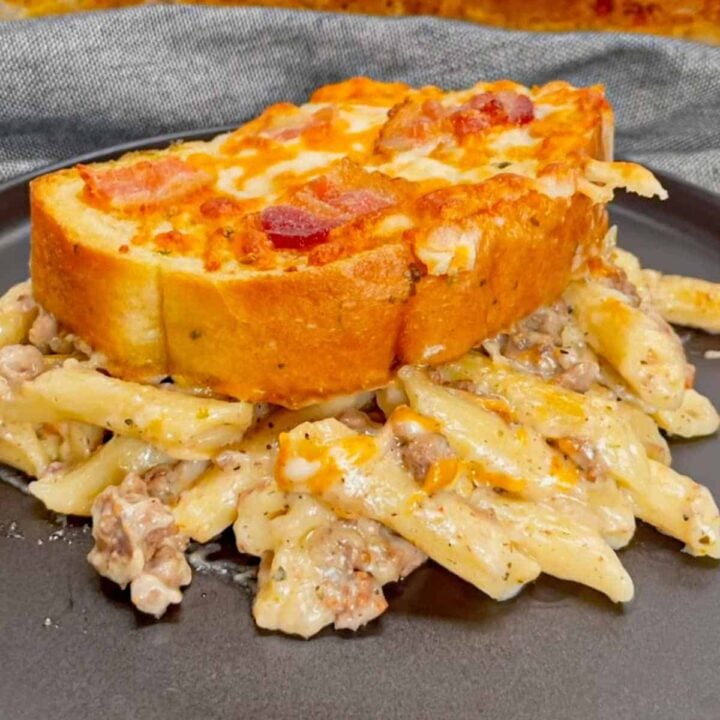 Dump and Bake Ground Beef Alfredo is an easy one pan dinner recipe perfect for weeknights. This creamy pasta recipe is made with store bought alfredo sauce, chicken broth, mini penne noodles, cream of bacon soup, ground beef, mozzarella and cheddar cheese, Texas toast garlic bread and bacon.
