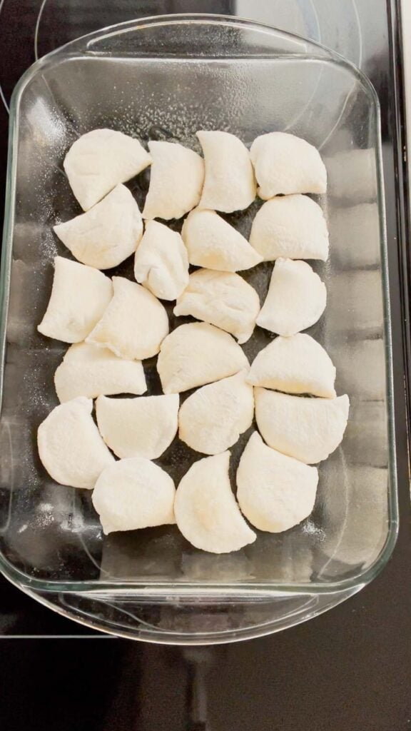 frozen pierogies in the bottom of a glass baking dish