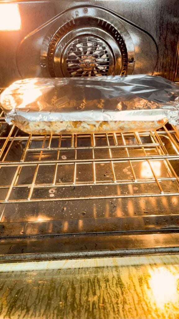 foil covered casserole dish baking in the oven