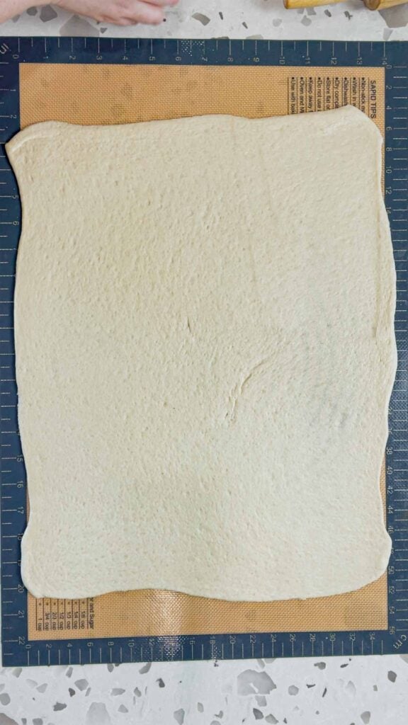 pizza dough rolled out on a silicone mat