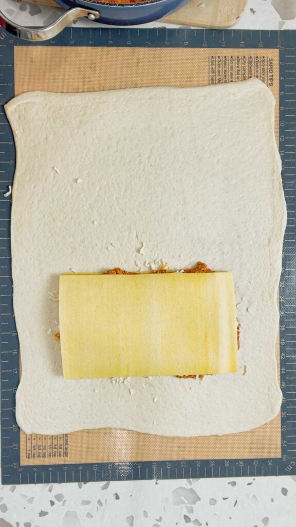 layering a lasagna on top of pizza dough