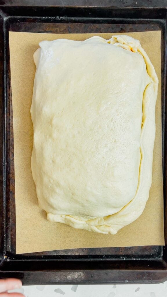 lasagna stuffed pizza dough on a parchment lined baking sheet