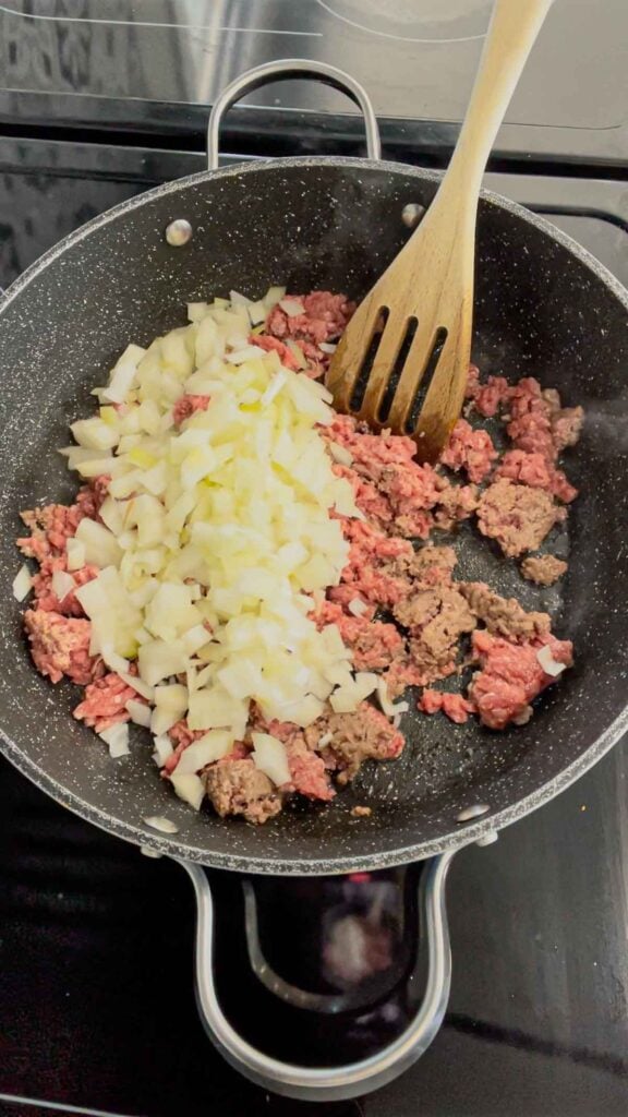 diced onions and ground beef cooking in a skillet