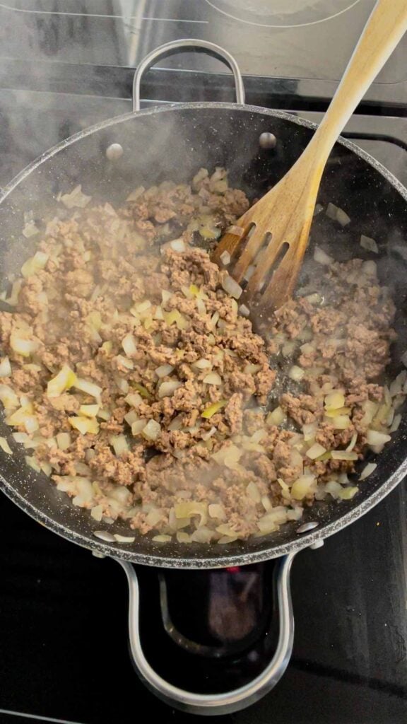 cooked ground beef and diced onions in a skillet