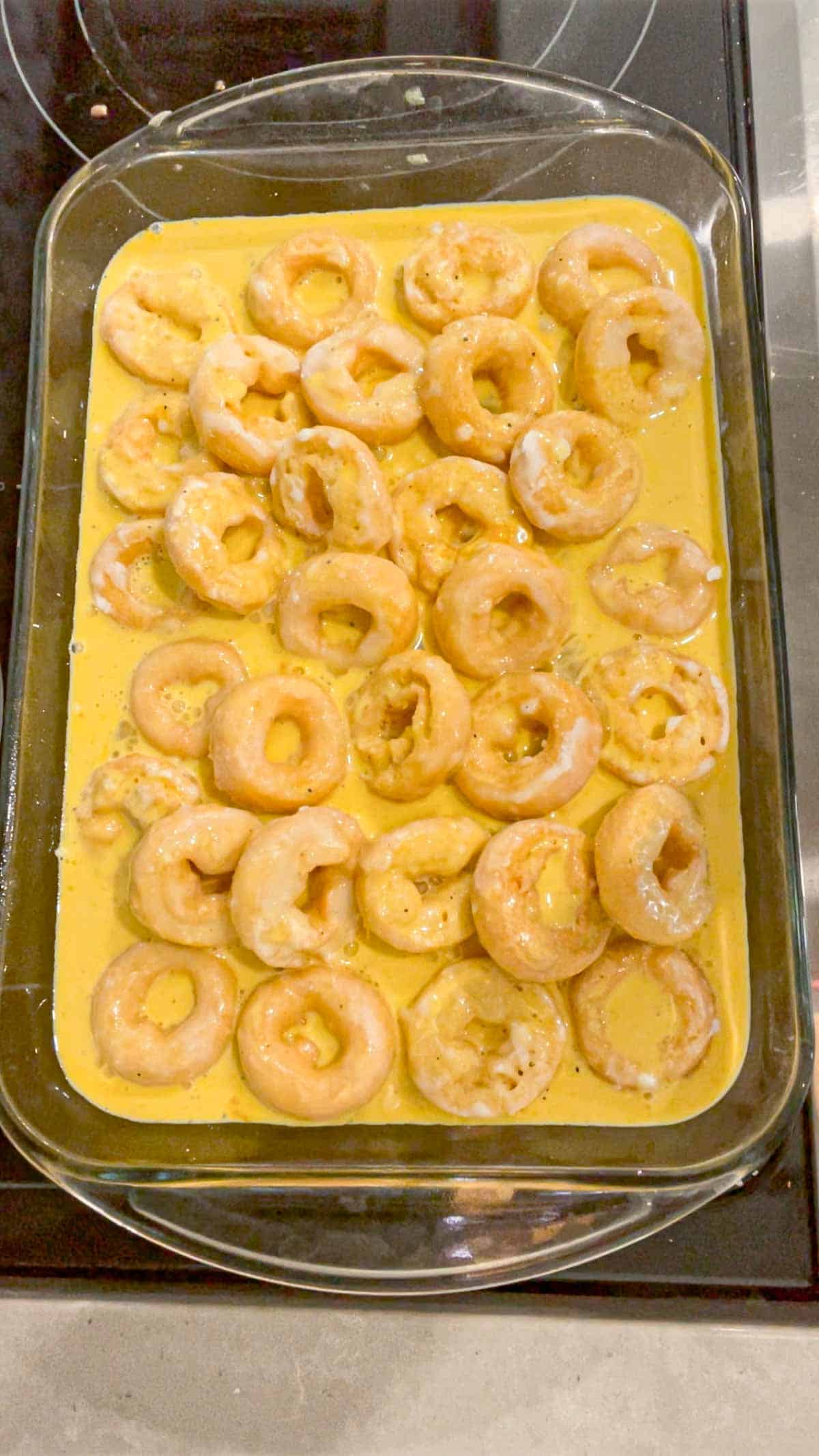 egg mixture poured over mini donuts in a baking dish