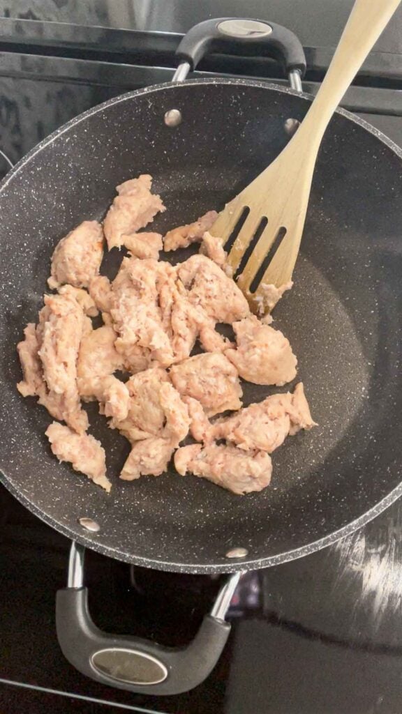 breaking apart raw sausage meat in a skillet