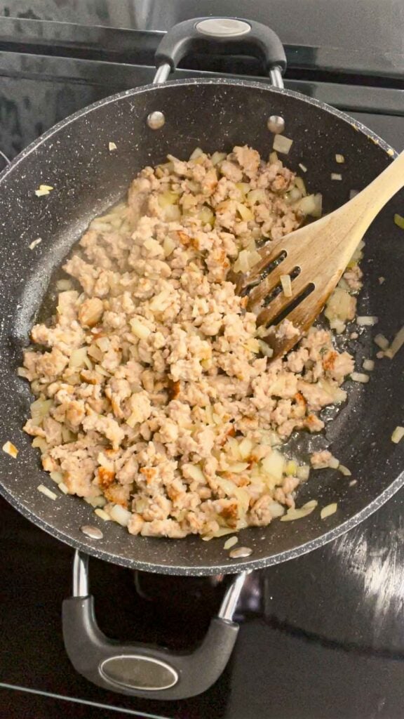 cooked sausage meat and diced onions in a skillet