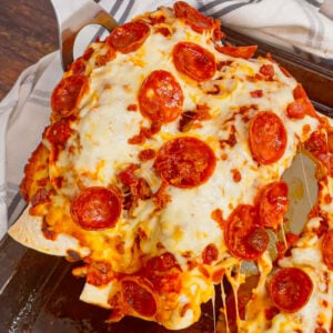 Pizza Enchiladas are a fun, family-friendly dinner recipe perfect for weeknights. Rolled flour tortillas are filled with ground beef, pepperoni, green peppers, onions and ricotta and baked with pizza sauce, mozzarella, pepperoni and bacon on top.
