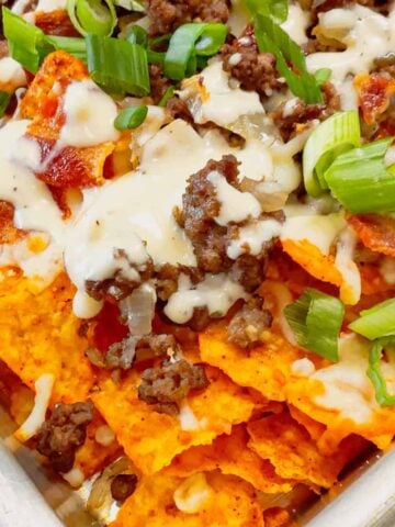 Beef and Bacon Cream Cheese Doritos Nachos are perfect for a fun and easy weeknight dinner or game day snack. These hearty nachos are loaded with seasoned beef, crispy bacon, mozzarella cheese, chopped green onions and drizzled with a rich cream cheese ranch sauce.