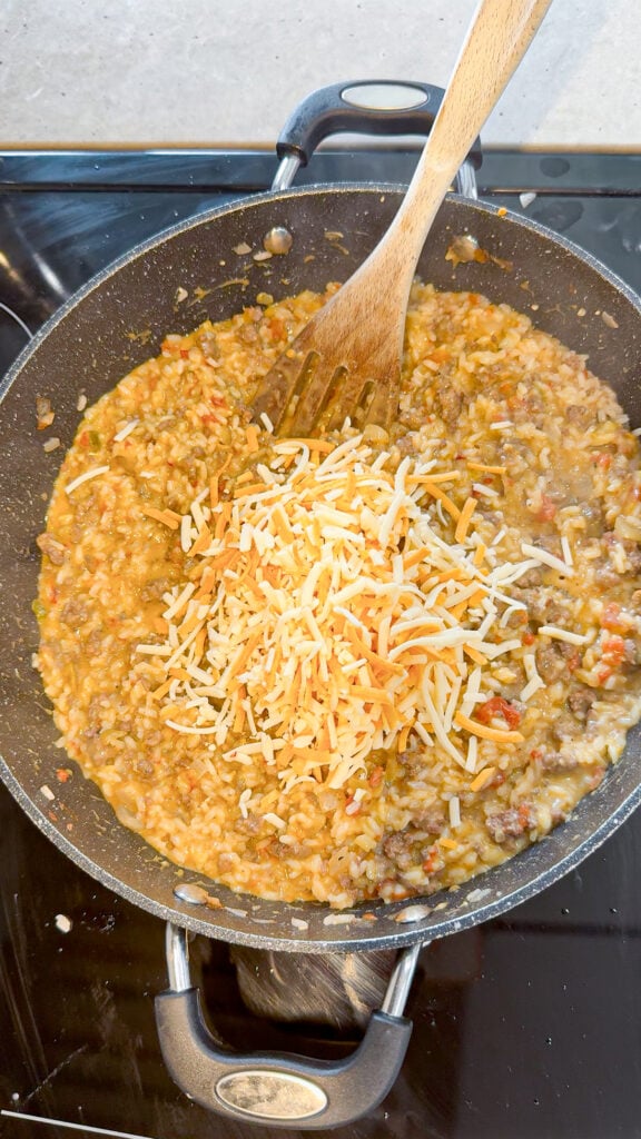 shredded nacho cheese added to a skillet with ground beef and rice