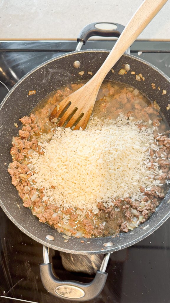 minute rice added to a skillet with cooked ground beef and chicken broth