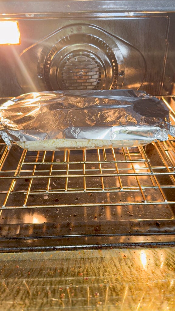 chicken alfredo pierogi casserole covered in foil baking in the oven