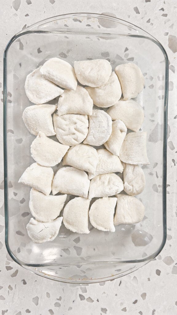frozen pierogies in the bottom of a glass baking dish