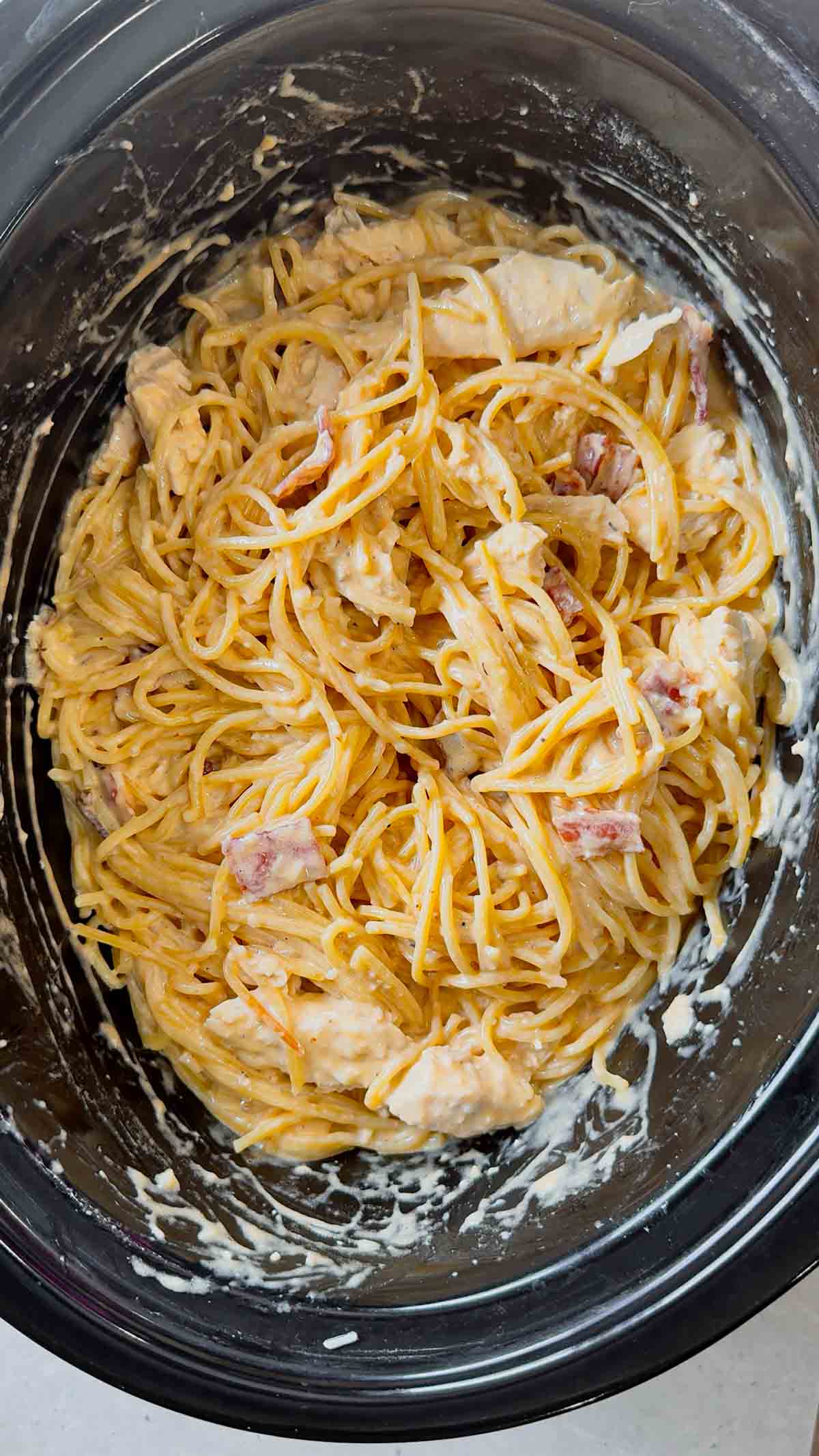 Crock Pot BBQ Alfredo Chicken Spaghetti is a flavourful pasta recipe the whole family will love. This slow cooker spaghetti recipe is loaded with chicken breast chunks and chopped bacon and is all tossed in a creamy garlic parmesan alfredo sauce with some barbecue sauce added for a fun flavour twist.