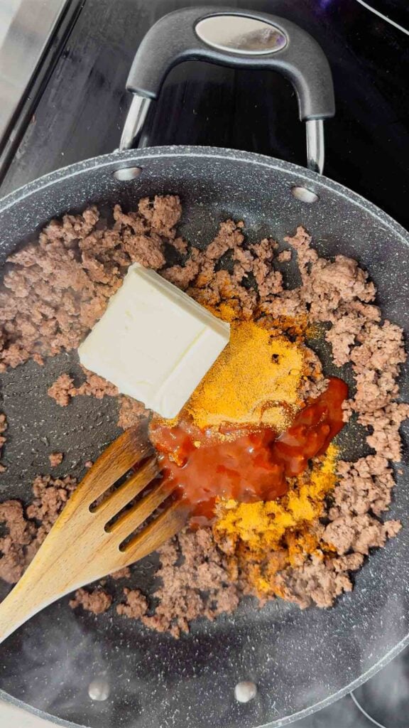 taco sauce, taco seasoning, cream cheese and cooked ground beef in a skillet