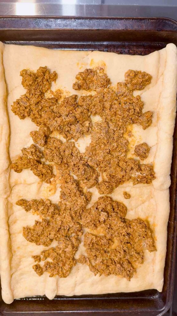 cream cheese and taco meat mixture spooned over crescent roll pizza crust