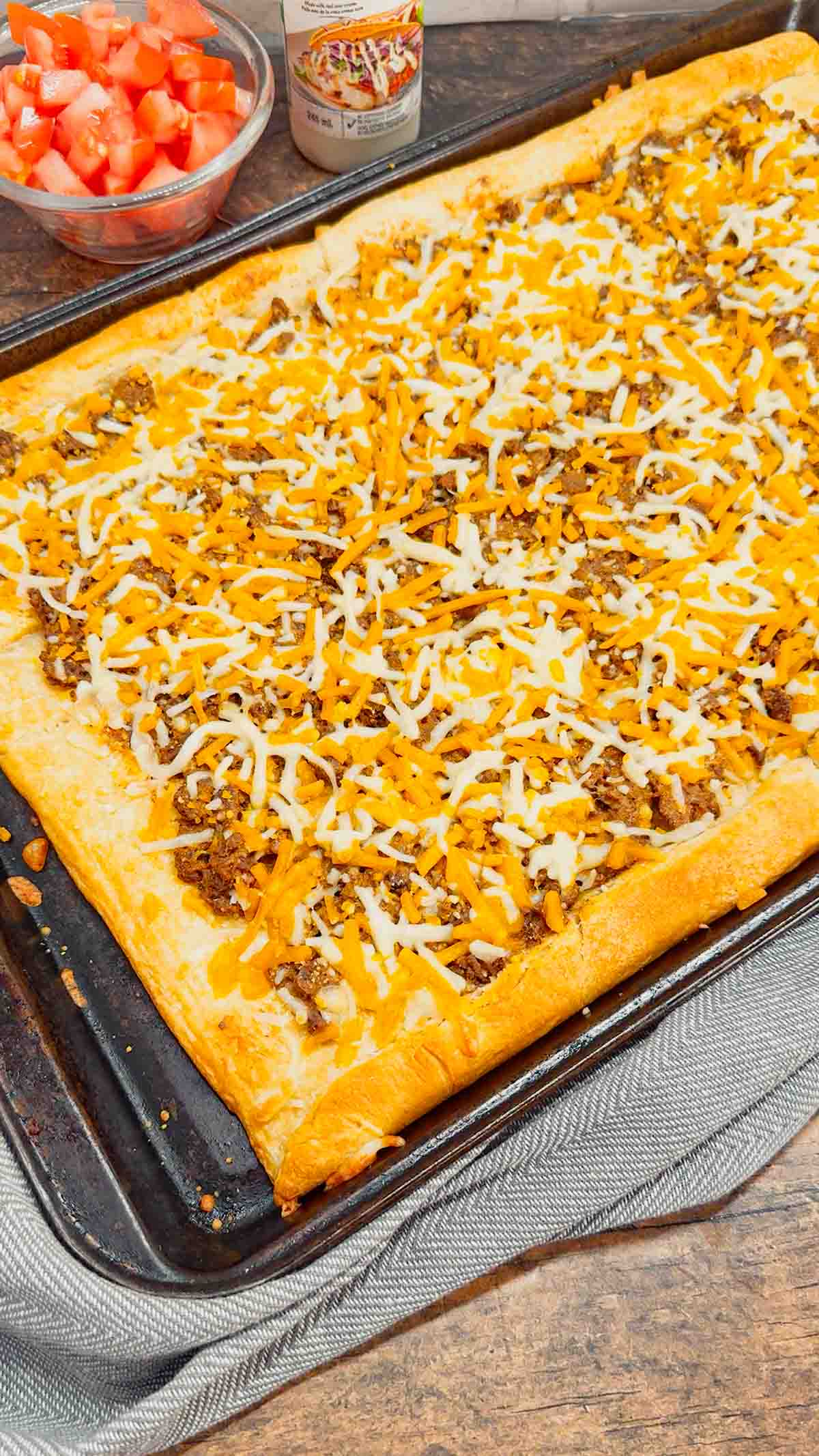 Taco Pizza with Crescent Rolls is a family friendly ground beef dinner recipe perfect for busy weeknights. This tasty pizza starts of with a Pillsbury crescent roll crust and is topped with a ground beef and cream cheese taco mixture, shredded nacho cheese, lettuce, tomatoes and mini Doritos nacho chips.
