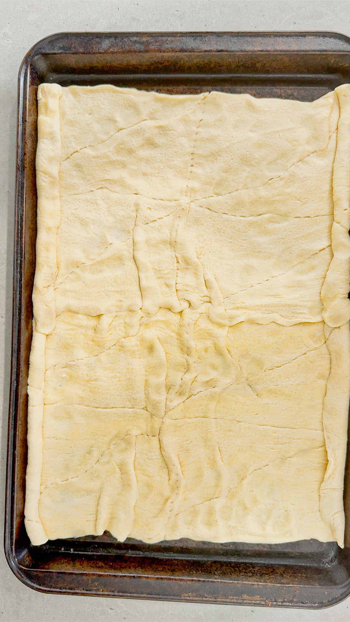 crescent roll dough rolled out on baking sheet