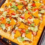 Taco Pizza with Crescent Rolls is a family friendly ground beef dinner recipe perfect for busy weeknights. This tasty pizza starts of with a Pillsbury crescent roll crust and is topped with a ground beef and cream cheese taco mixture, shredded nacho cheese, lettuce, tomatoes and mini Doritos nacho chips.