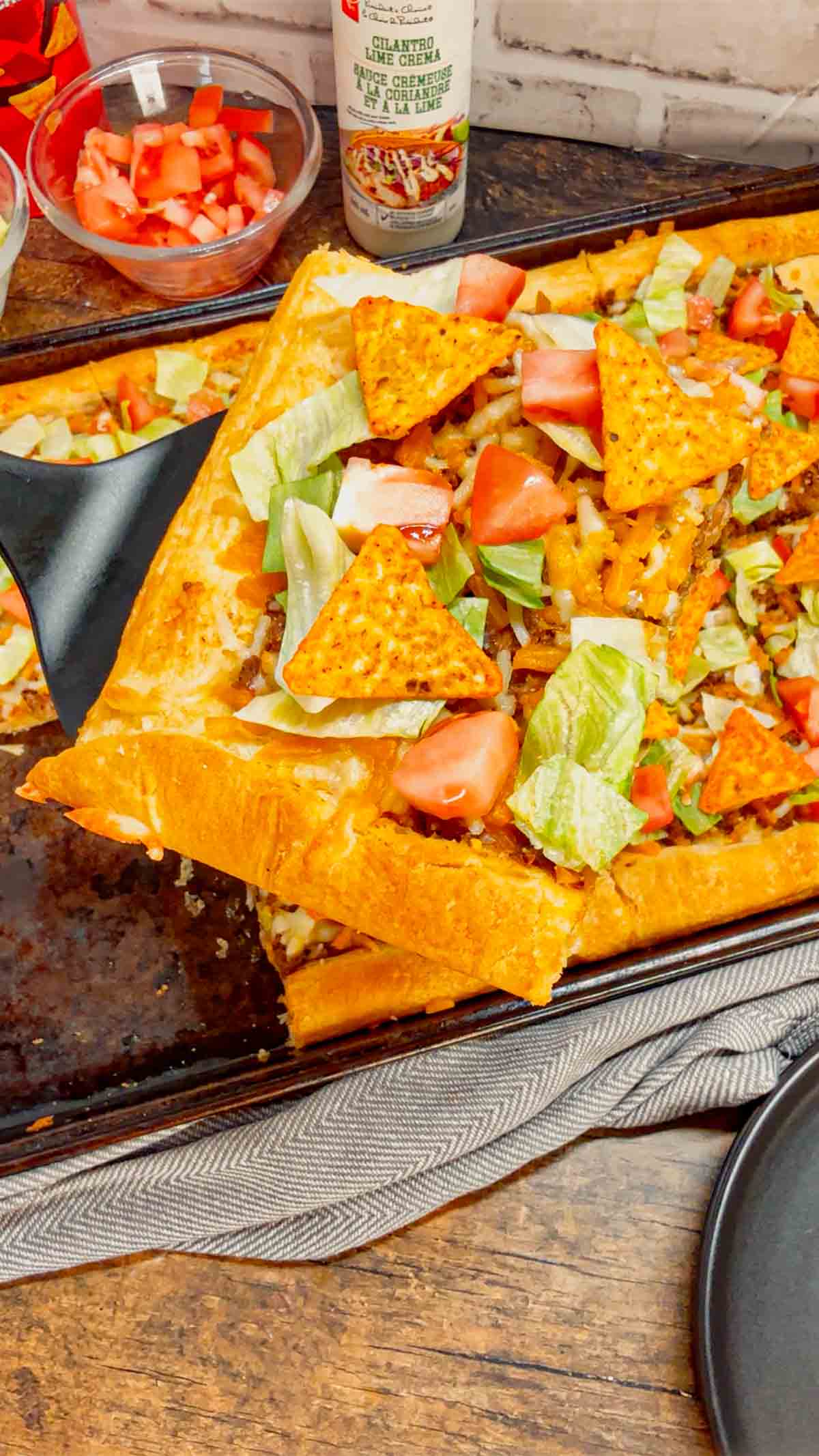 Taco Pizza with Crescent Rolls is a family friendly ground beef dinner recipe perfect for busy weeknights. This tasty pizza starts of with a Pillsbury crescent roll crust and is topped with a ground beef and cream cheese taco mixture, shredded nacho cheese, lettuce, tomatoes and mini Doritos nacho chips.