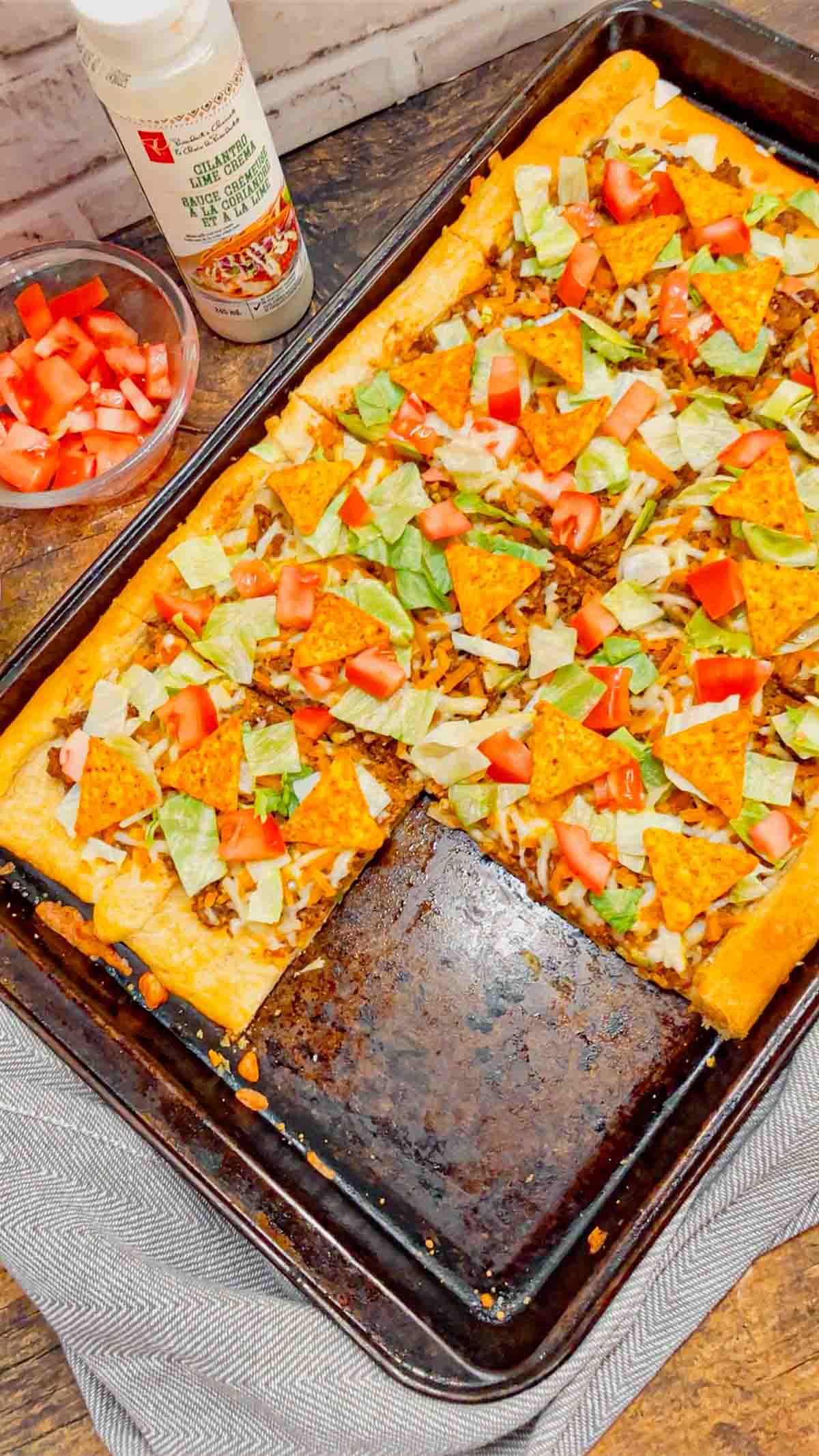 Taco Pizza with Crescent Rolls is a family friendly ground beef dinner recipe perfect for busy weeknights. This tasty pizza starts of with a Pillsbury crescent roll crust and is topped with a ground beef and cream cheese taco mixture, shredded nacho cheese, lettuce, tomatoes and mini Doritos nacho chips.