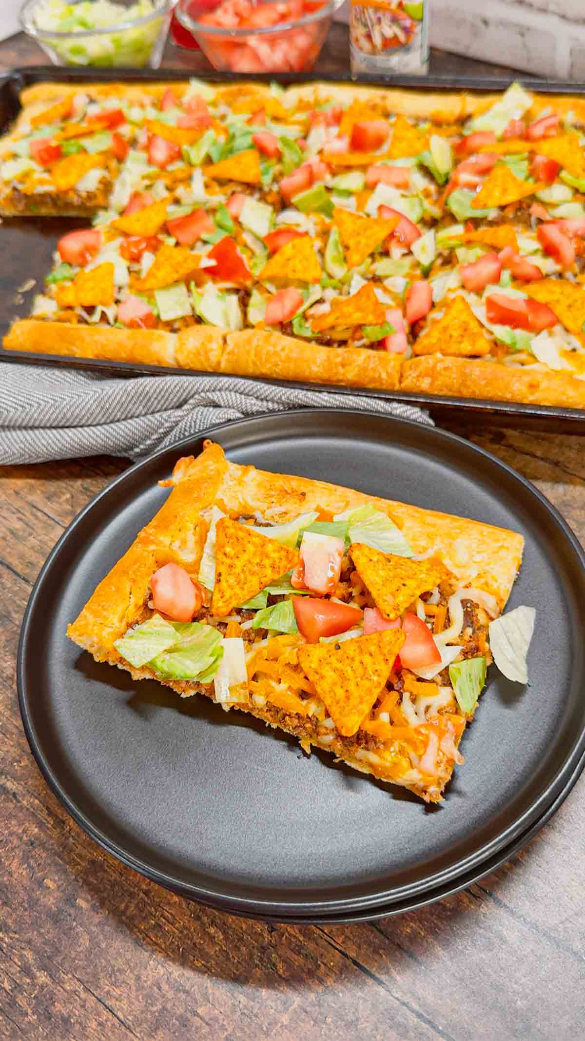 Taco Pizza with Crescent Rolls is a family friendly ground beef dinner recipe perfect for busy weeknights. This tasty pizza starts of with a Pillsbury crescent roll crust and is topped with a ground beef and cream cheese taco mixture, shredded nacho cheese, lettuce, tomatoes and mini Doritos nacho chips.