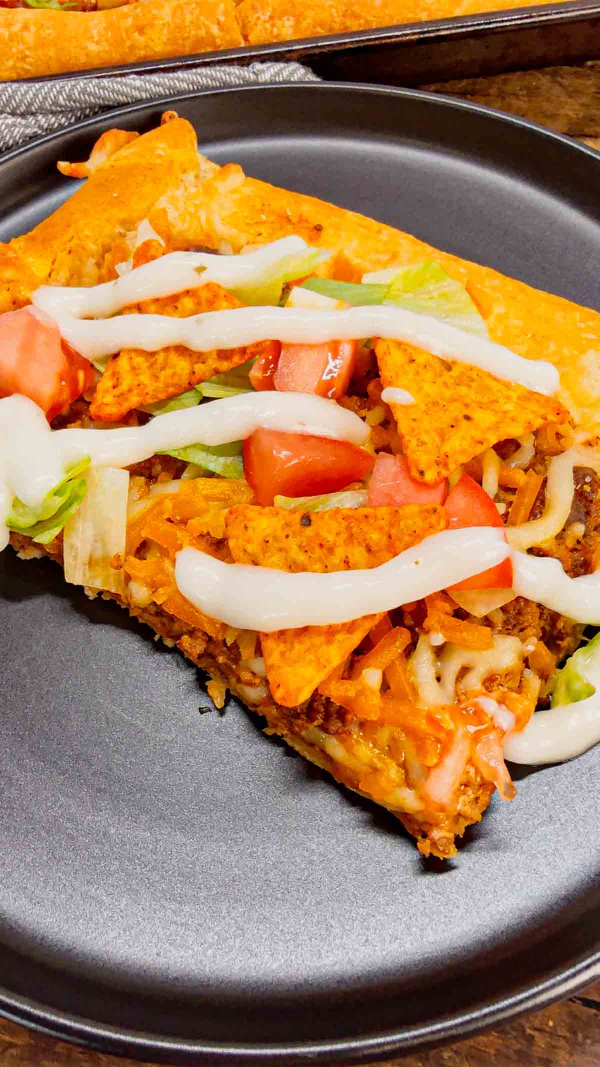 Taco Pizza with Crescent Rolls is a family friendly ground beef dinner recipe perfect for busy weeknights. This tasty pizza starts of with a Pillsbury crescent roll crust and is topped with a ground beef and cream cheese taco mixture, shredded nacho cheese, lettuce, tomatoes and mini Doritos nacho chips.